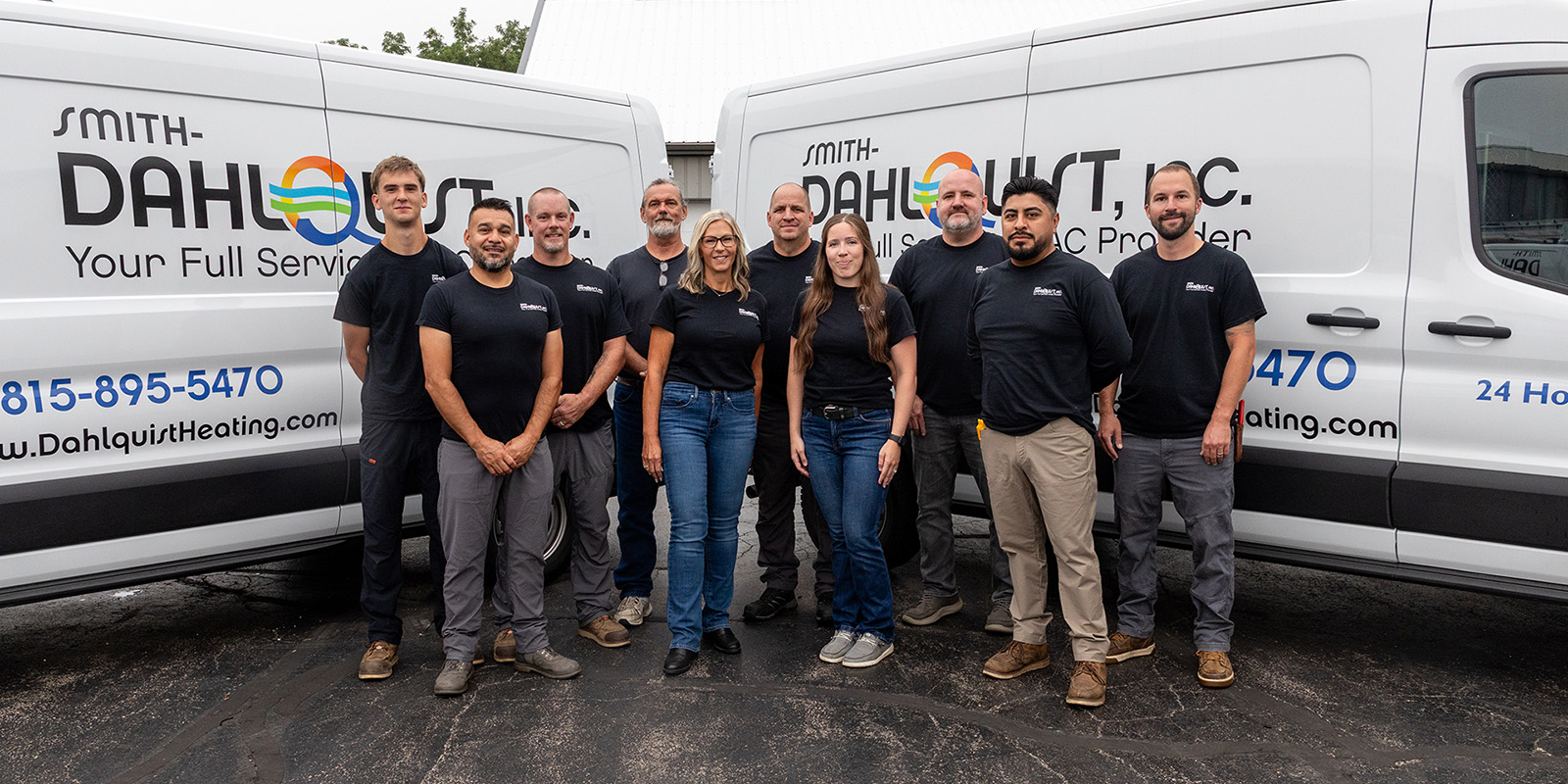 Smith-Dahlquist group photo, posing in front of two company vans